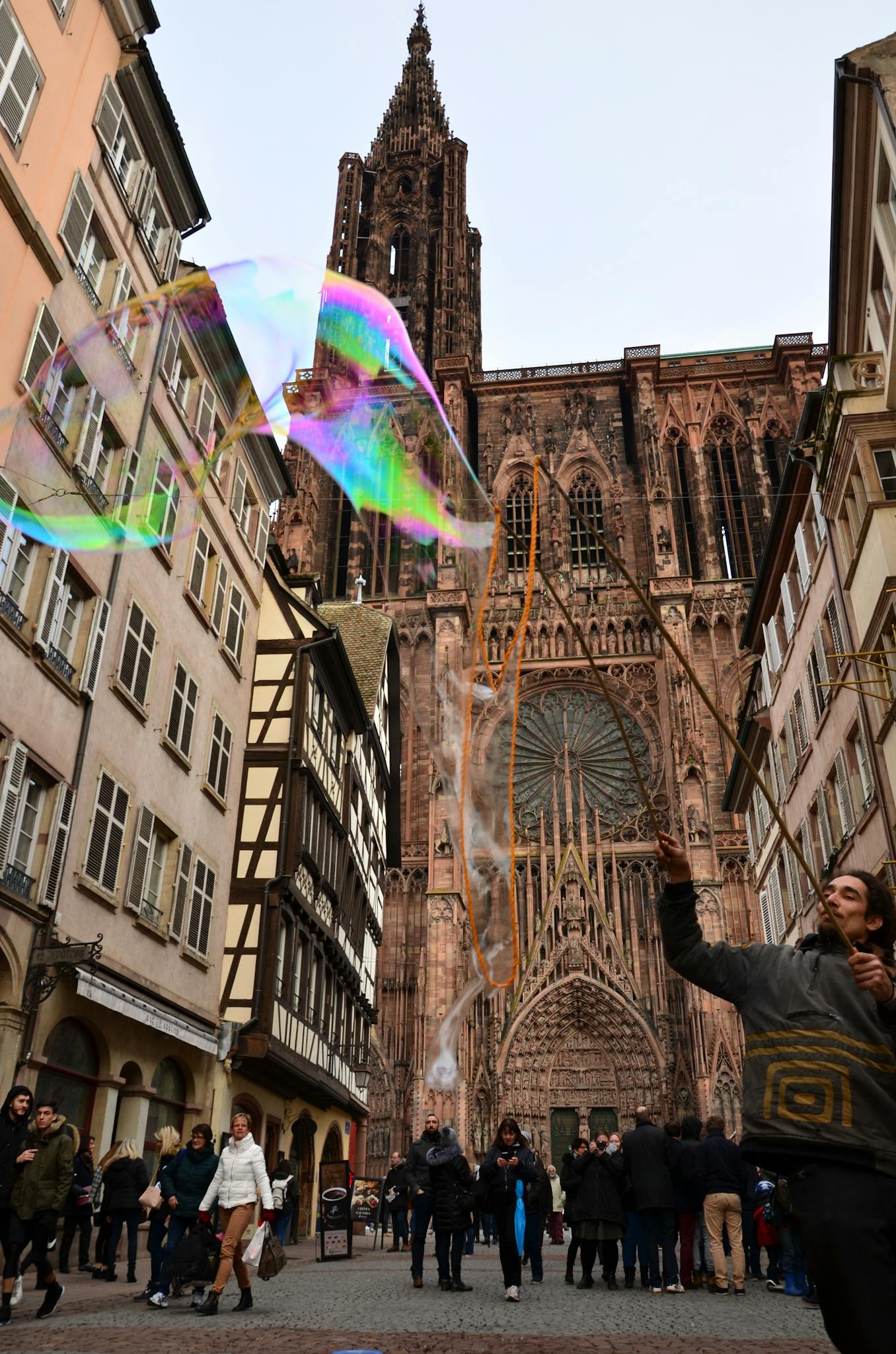 Street view of Strasbourg Cathedral with a performer making bubbles, capturing the urban ambiance.